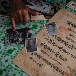 South Korean Lee Su-nam shows a selection of ageing family photos and his brother’s high school diploma. Photograph: Benjamin Haas 