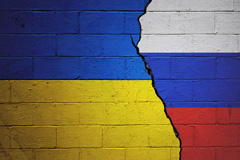 Ukraine and Russian flags on a cracked brick wall