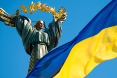 Monument of Independence - a column with a figure of a woman with a branch of a guelder-rose on her hands. In the foreground the Ukrainian flag