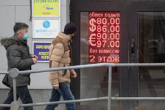 Two men on the street outside a building with the exchange rate in neon signs