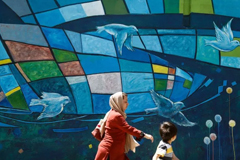 An Iranian woman and child walk past a mural in downtown Tehran on April 27, 2016. Atta Kenare/AFP/Getty Images