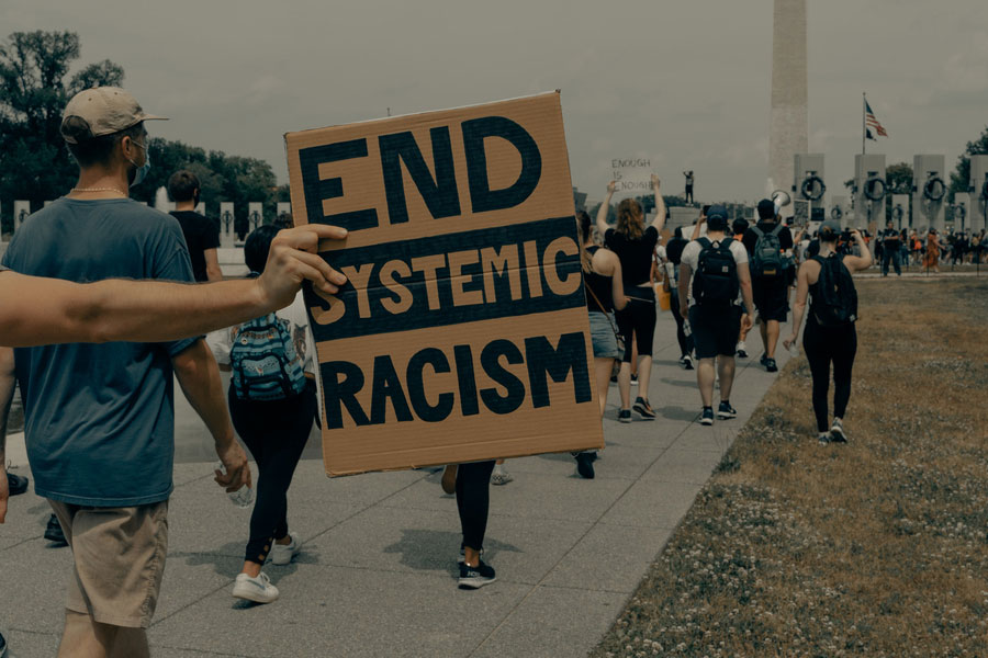 Protestors holding up a sign that reads: End Systemic Racism