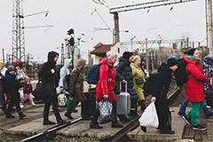 Having just disembarked a train, people walk with their luggage across the tracks in Lviv.