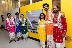 Six people wearing traditional South Asian clothing in front of the exhibition sign