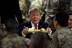 Trump holding a plate of food surrounded by US Troops - OLIVIER DOULIERY/AFP/GETTY IMAGES