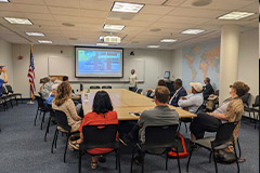 People listening to a presentation, seated around a table