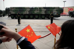 Spectators wave Chinese flags as military vehicles carrying DF-41 ballistic missiles roll during a parade to commemorate the 70th anniversary of the founding of Communist China in Beijing, Oct. 1, 2019. 