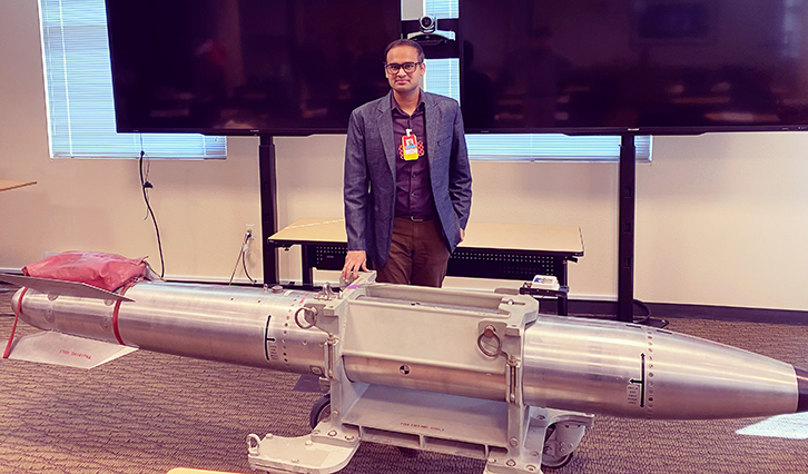 Caption: Kunal posing with a B61 nuclear bomb at Sandia National Laboratories in Albuquerque, New Mexico.